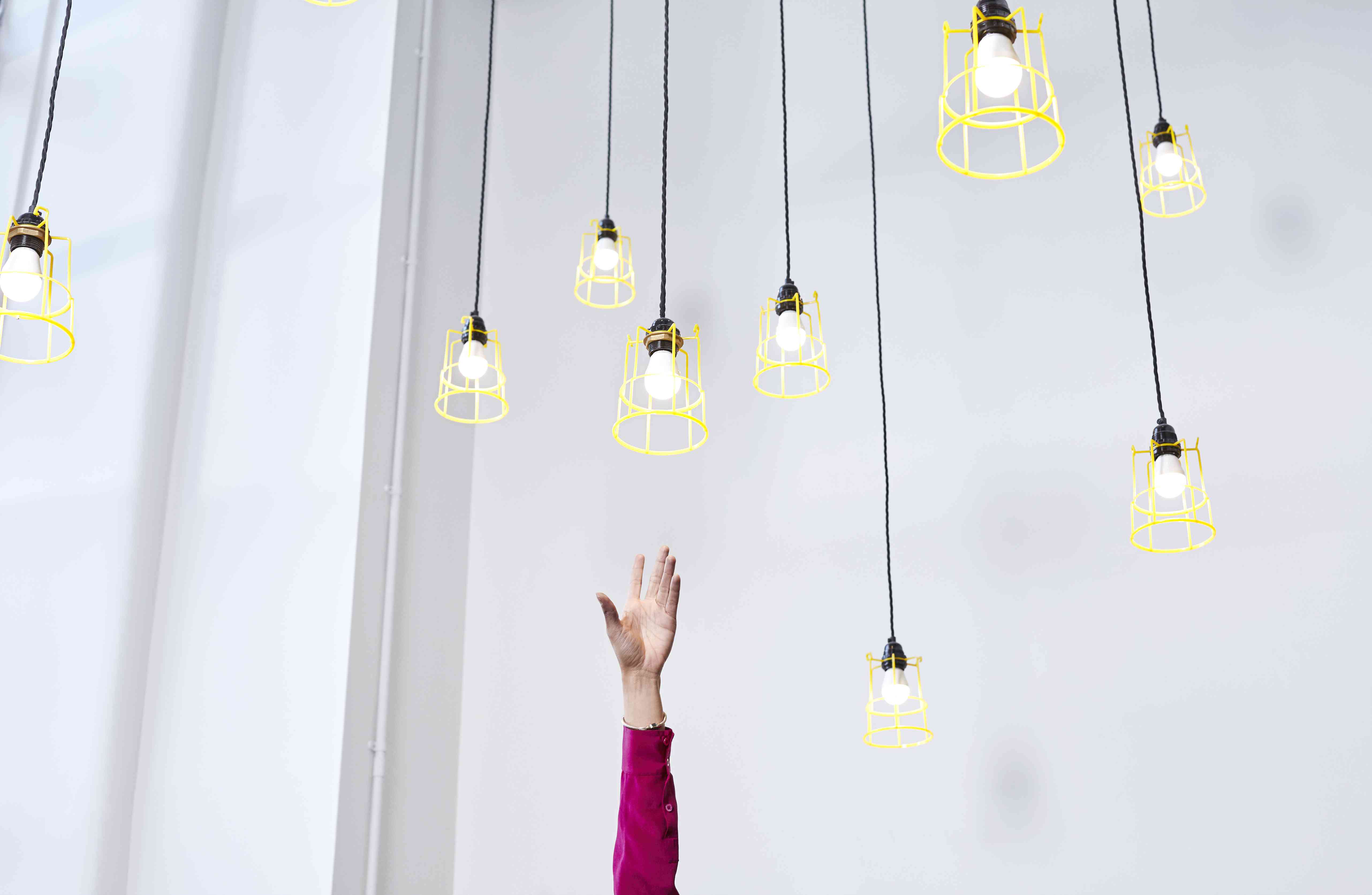 A hand reaching for conceptual idea lightbulbs