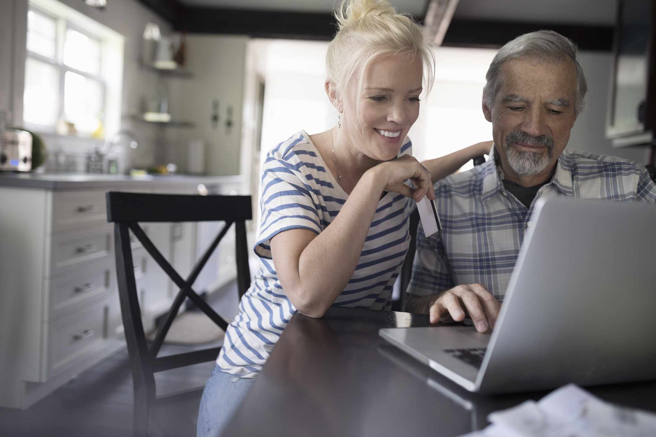 Daughter helping senior father using laptop.