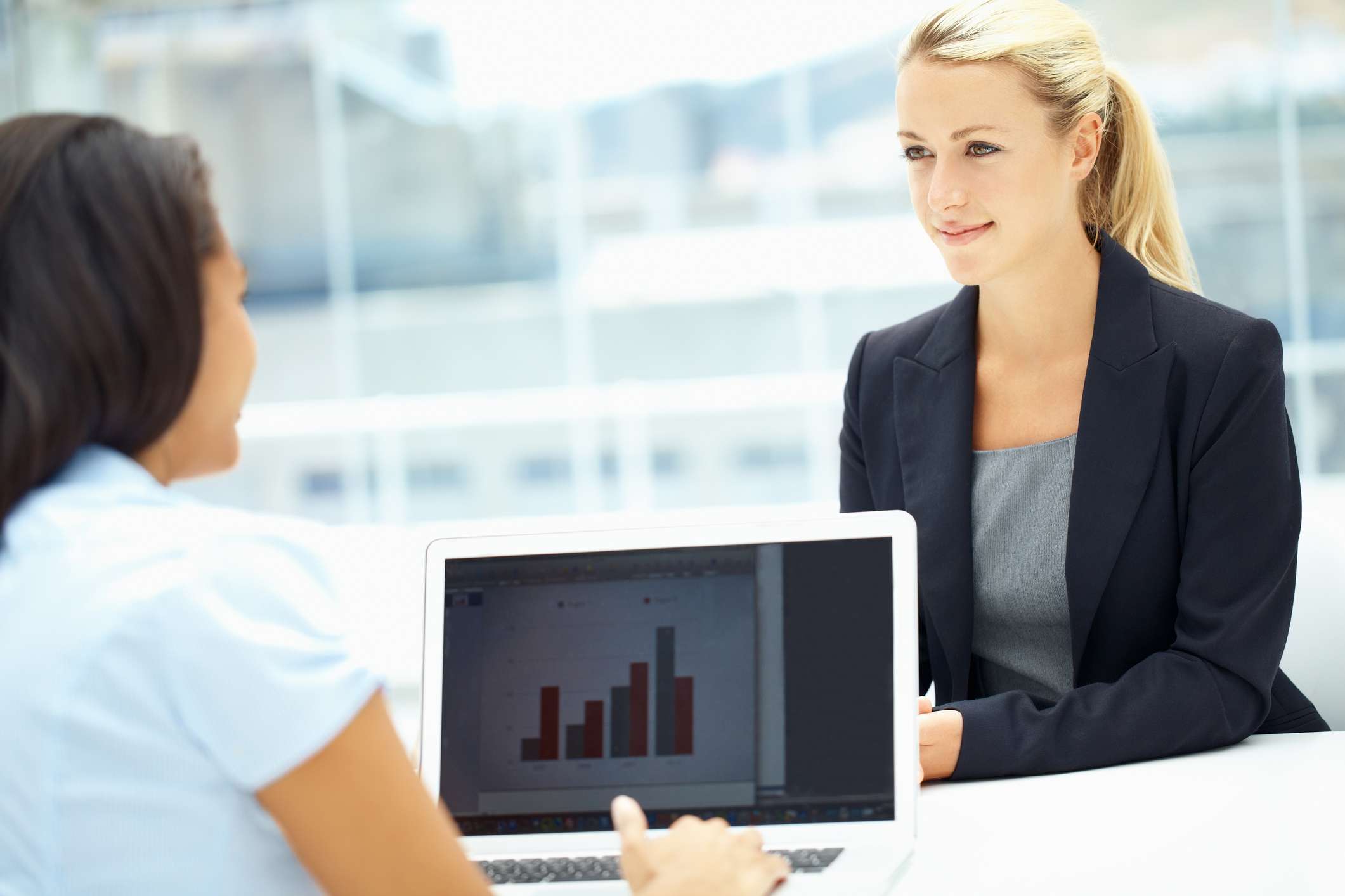 Two young executives having a meeting while working on a laptop.