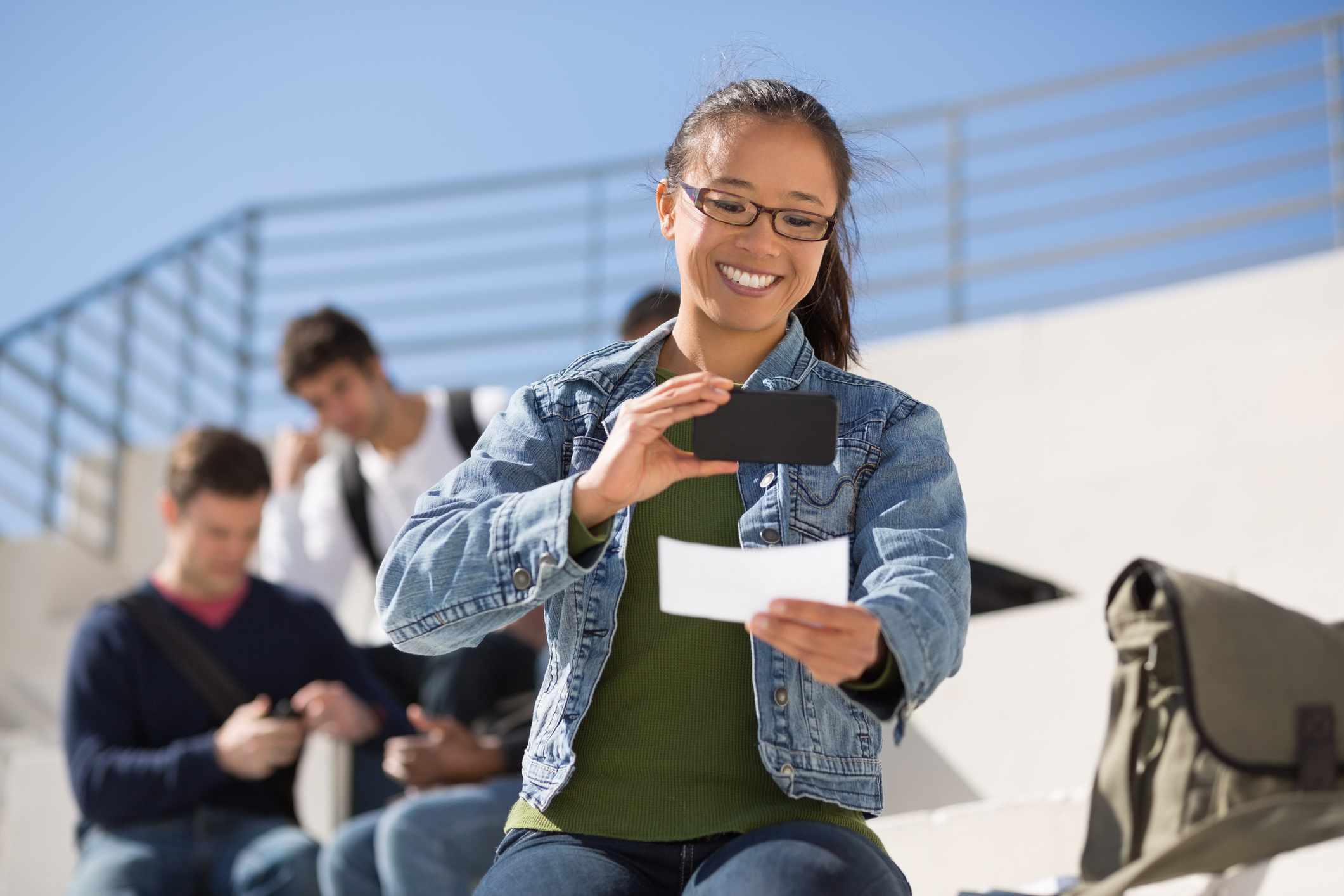 A young adult takes a photo of a check.