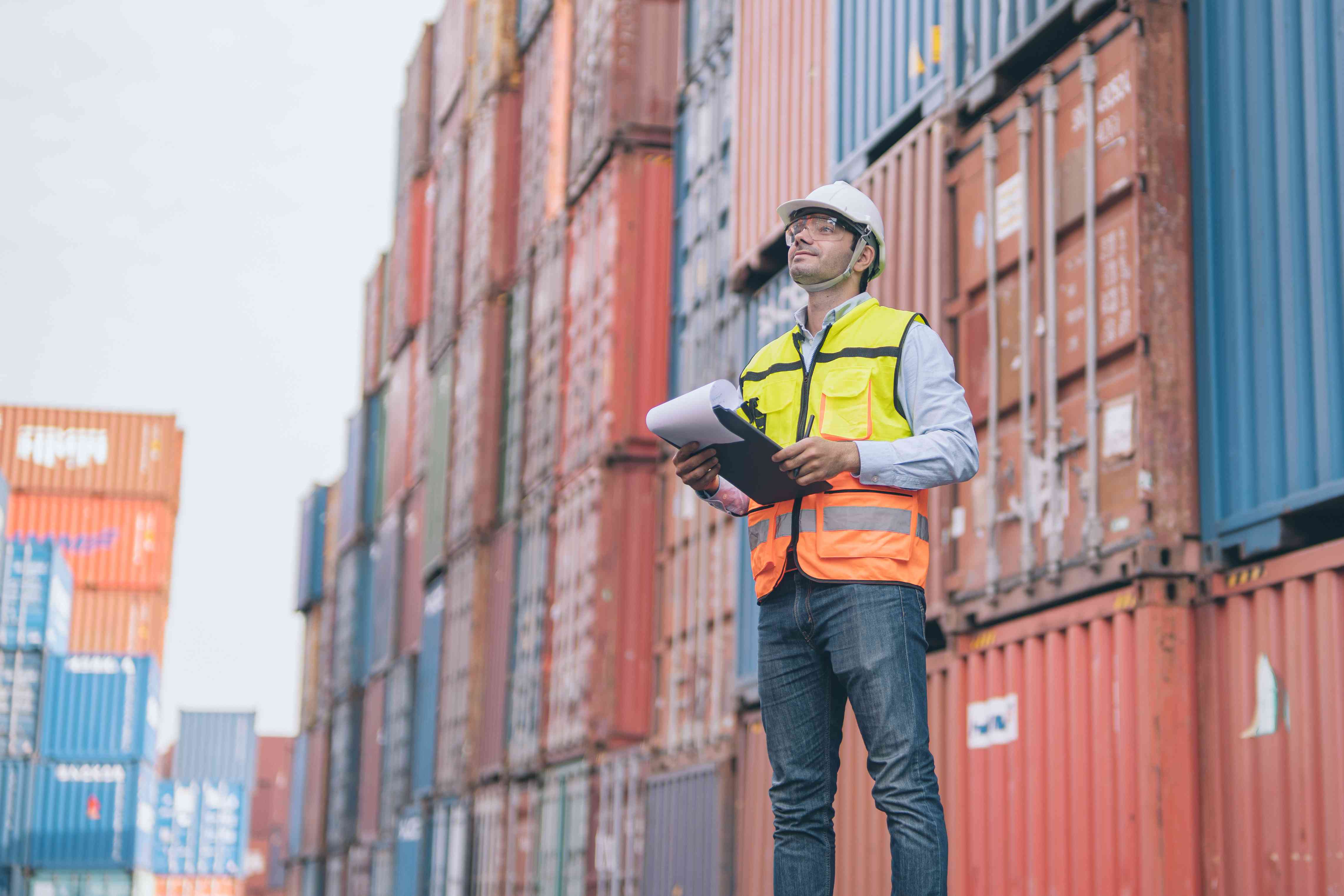 Dock worker examining through bill of lading for shipping containers.