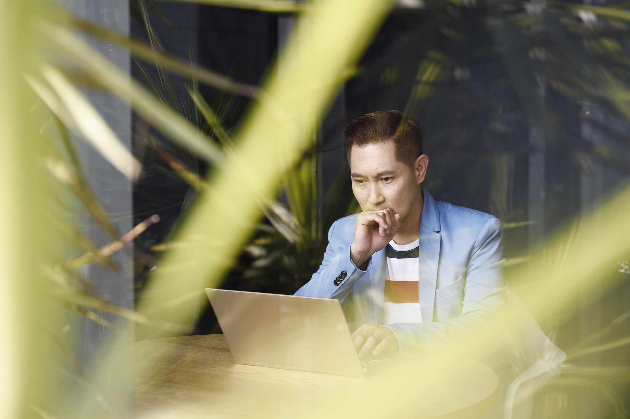 Man works on laptop amid green plants