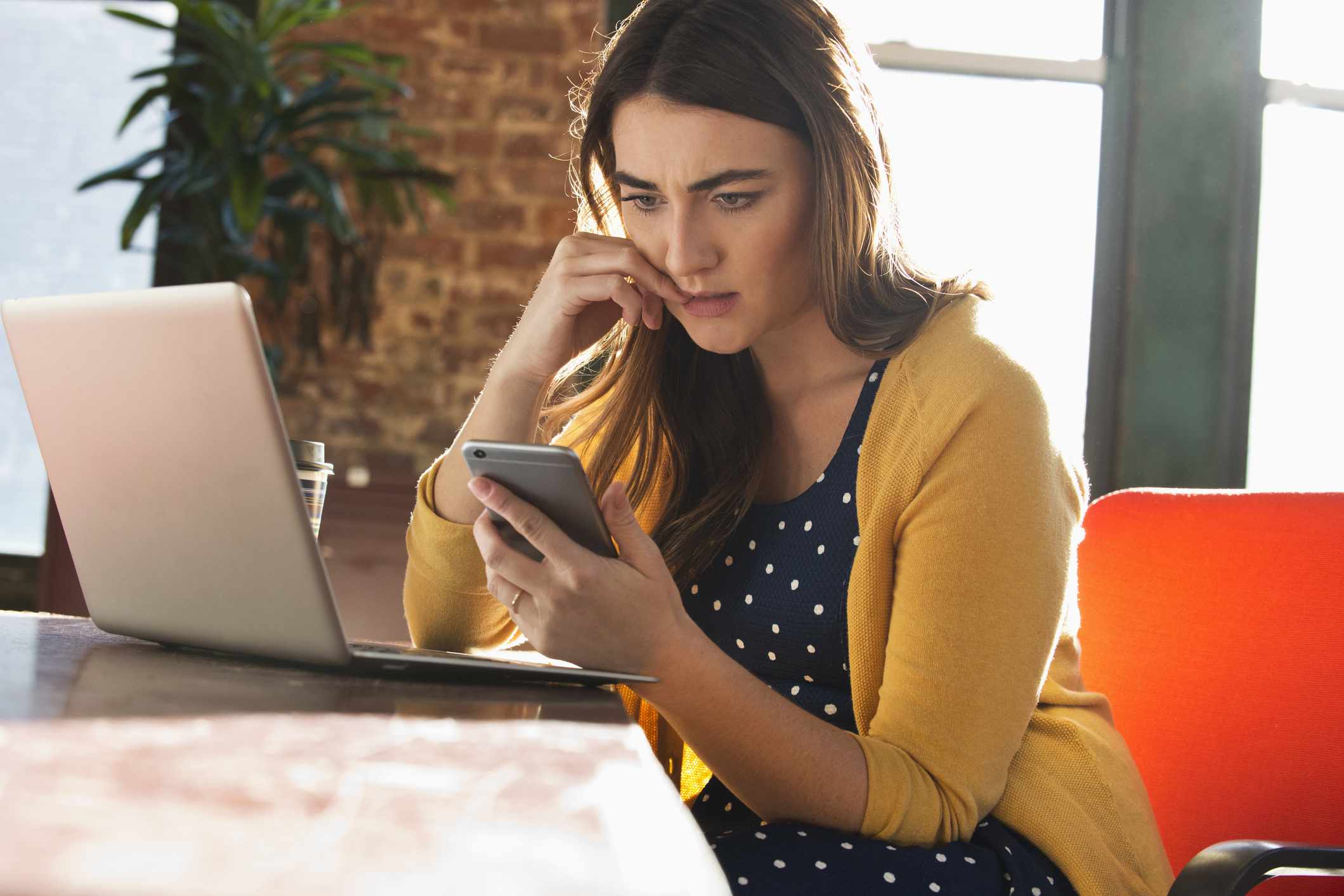 Woman Sitting at Desk Uses Phone